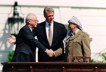Yitzhak Rabin and Yasir Arafat shake hands at 1993 White House peace signing with President Clinton. Photo courtesy of Wikipedia