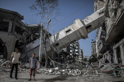 Palestinians walk next to the collapsed minaret of mosque in Gaza City, Gaza Strip, 30 July 2014. The mosque was destroyed in an overnight Israeli airstrike.  EPA/OLIVER WEIKEN and Amnesty International