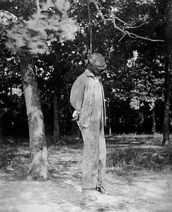 A man lynched from a tree. Face partially conc...