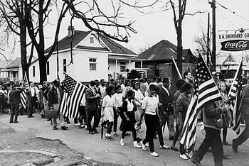Participants, some carrying American flags, ma...