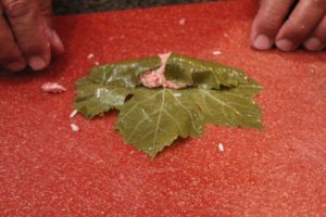 grape leaf being stuffed with rice and lamb